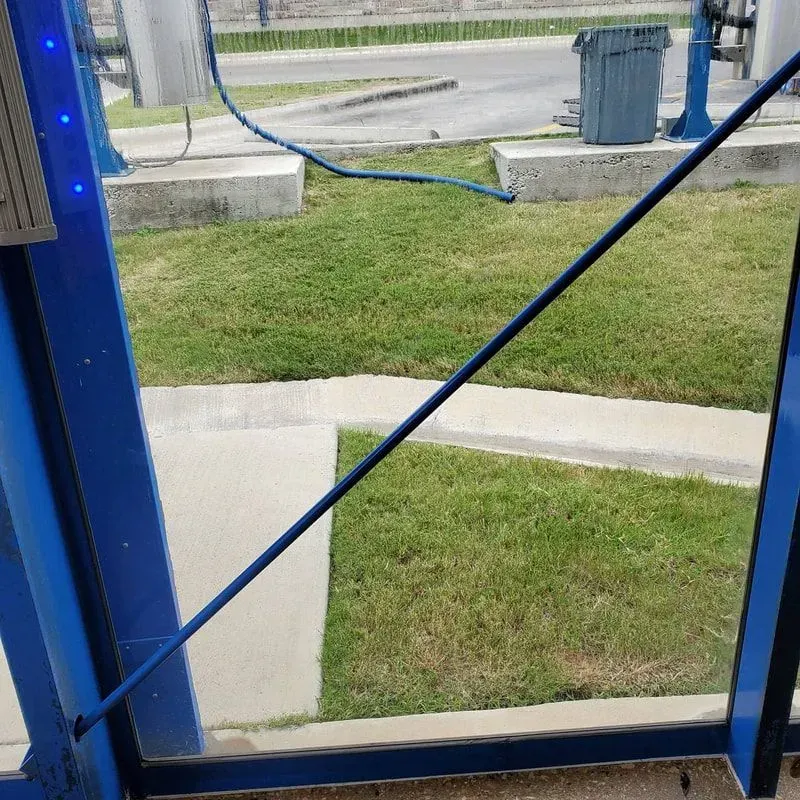 A hose is connected to a blue pole in the grass.
