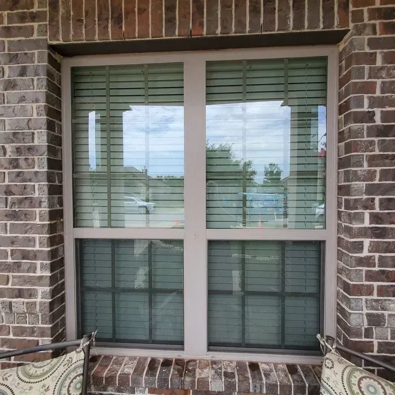 A brick building with a window with blinds on it
