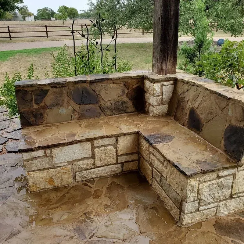 A stone bench is sitting on top of a stone patio.