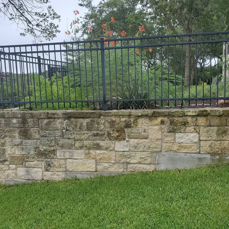 A brick wall with a metal fence surrounding it