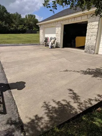 A concrete driveway leading to a garage with a white garage door.