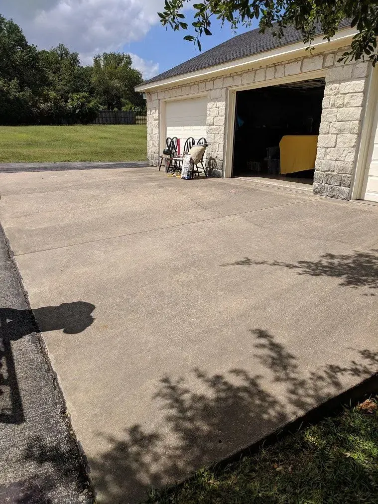 A concrete driveway with a garage in the background.