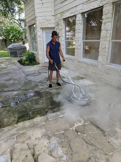 A man is cleaning a stone patio with a pressure washer.