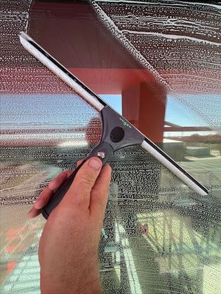 A person is holding a window squeegee in front of a window.