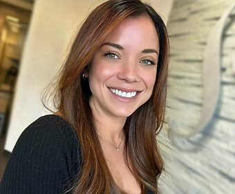 A woman with long brown hair is smiling and wearing a black shirt.