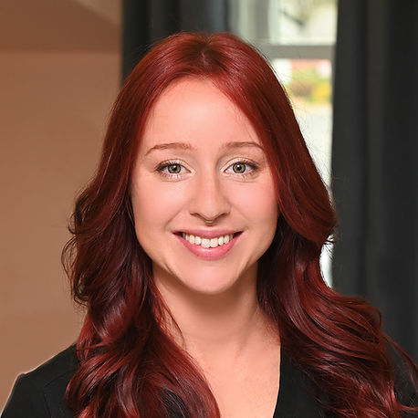 A woman with red hair is smiling and wearing a black jacket.
