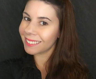 A woman with long brown hair is smiling and wearing a black shirt.