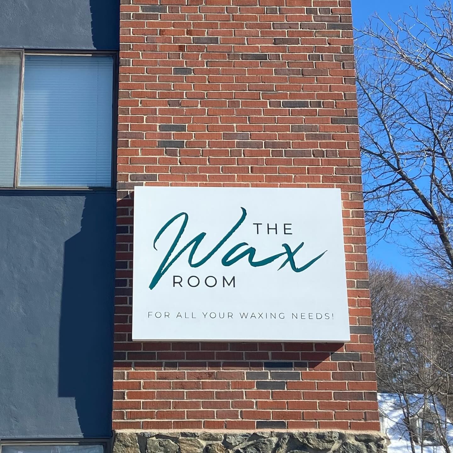 A brick building with a sign that says the wax room