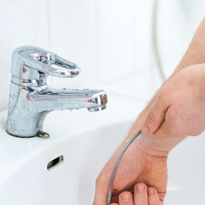 A man is fixing a sink with a pair of pliers.