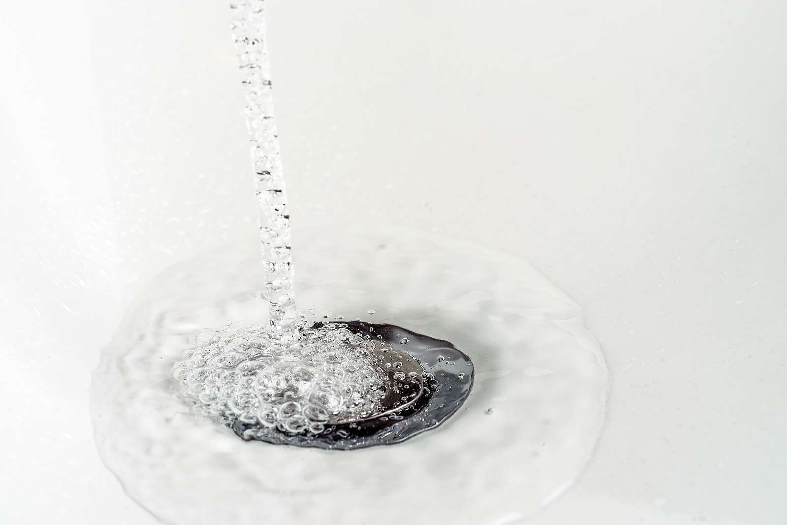 Water is pouring down a drain in a bathtub.