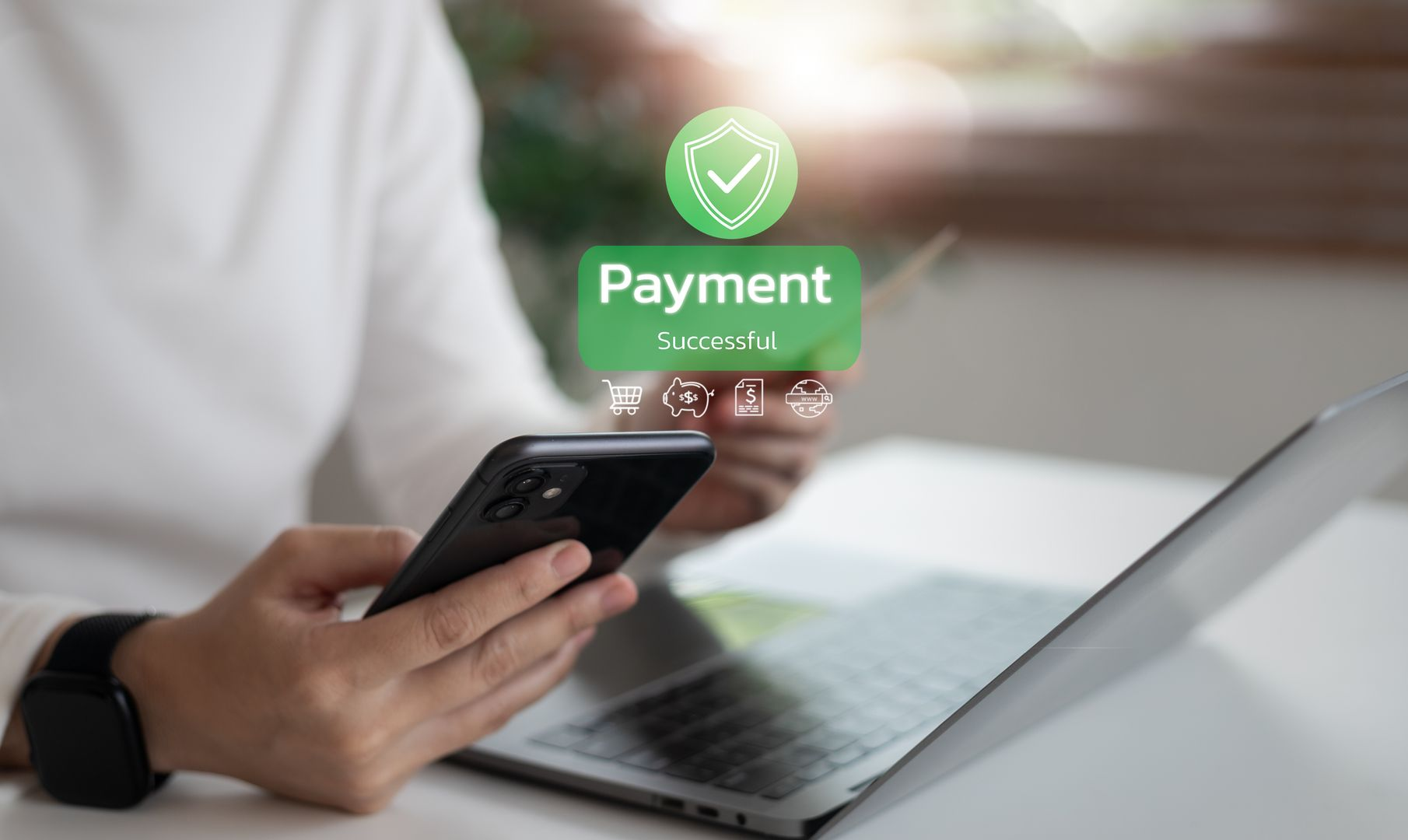 Person holding phone and credit card, making online payment via laptop.