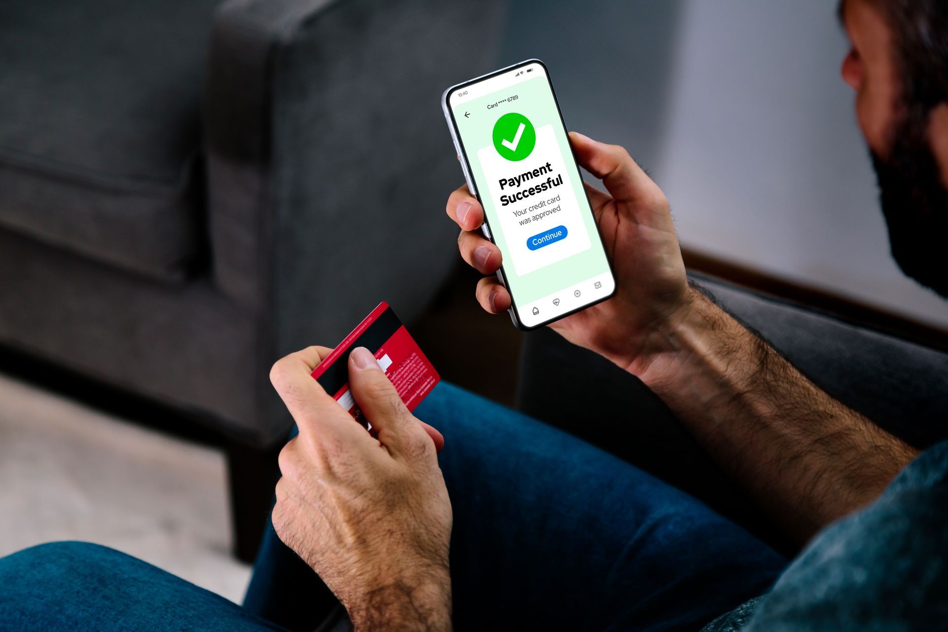 Person holding a credit card and smartphone displaying a successful payment confirmation.