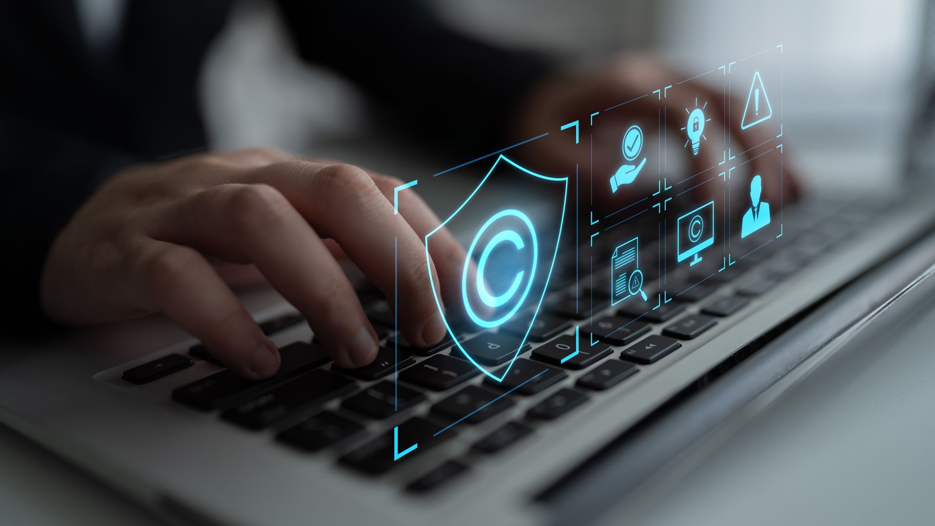 Hands typing on laptop keyboard with digital copyright shield overlay.
