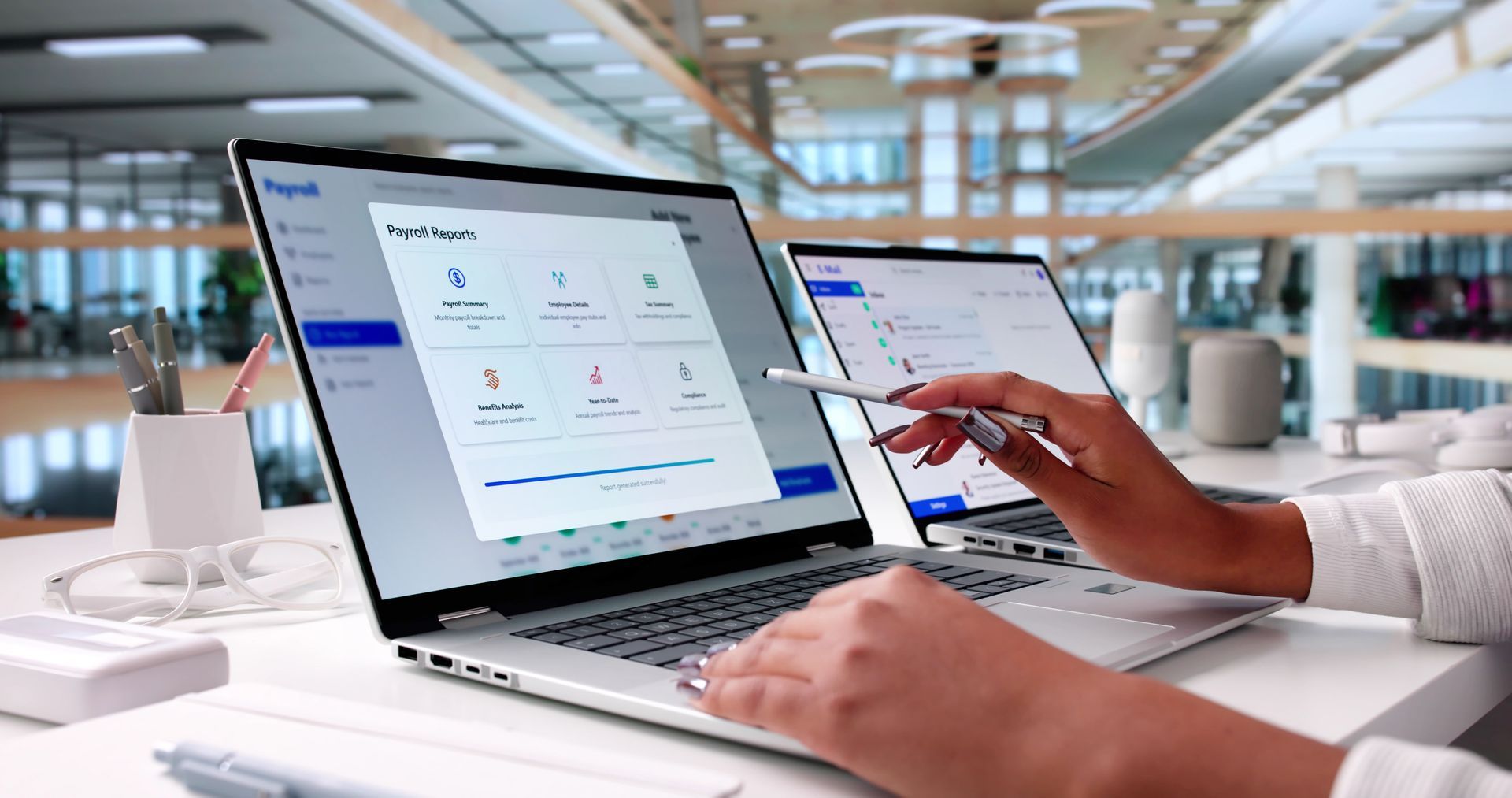 Person using a laptop with a stylus. Displays a software interface in an office setting.
