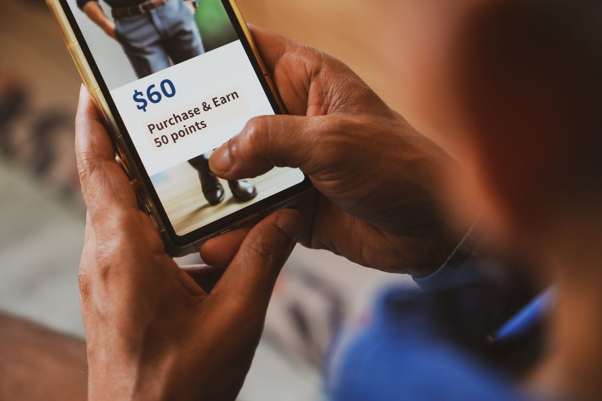 Person holding a phone displaying a shopping rewards offer: spend $60, earn 50 points.