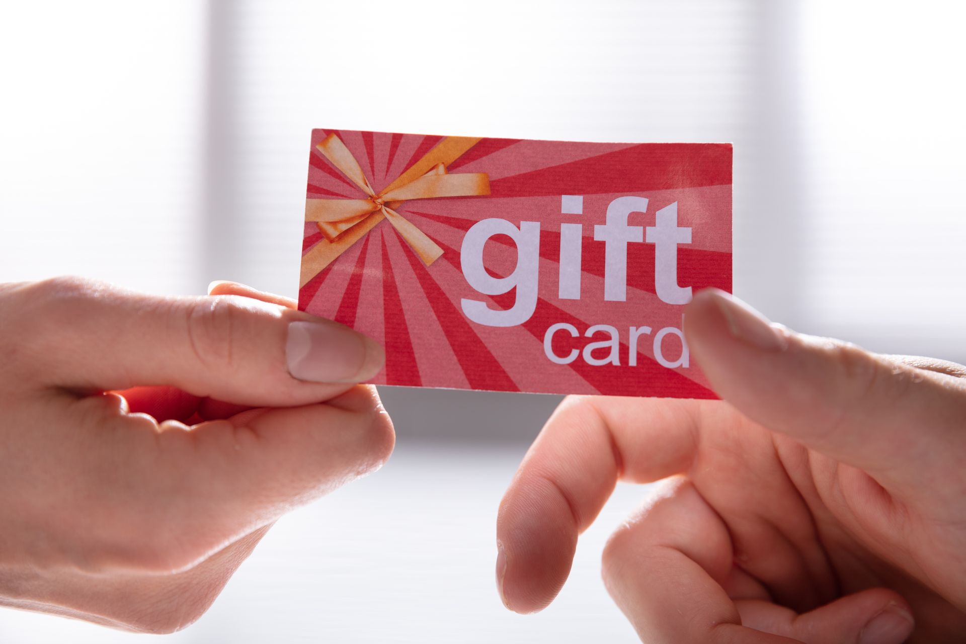 Two hands holding a red and orange gift card with 