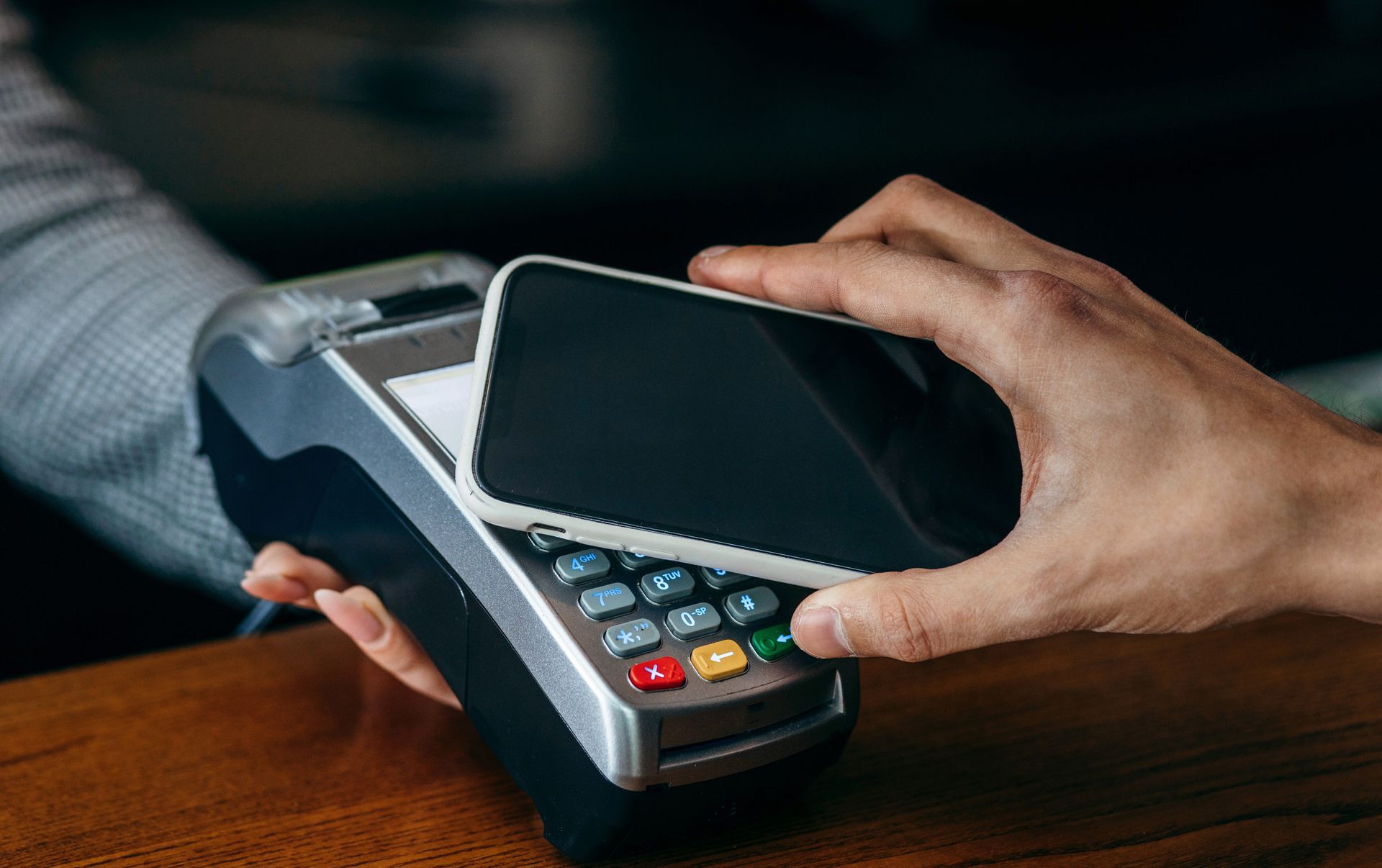 Smartphone held over a point-of-sale device for contactless payment.