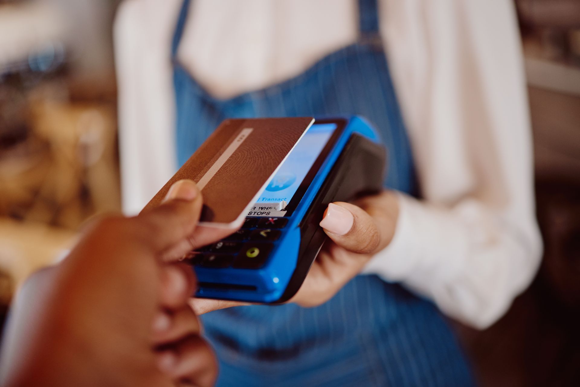 Person using a contactless payment card at a point-of-sale terminal.