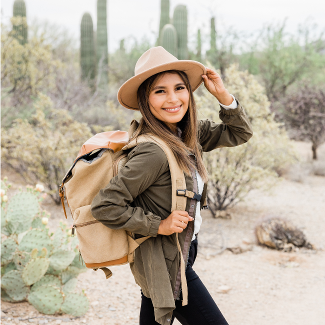 a woman wearing a hat and carrying a backpack in the desert