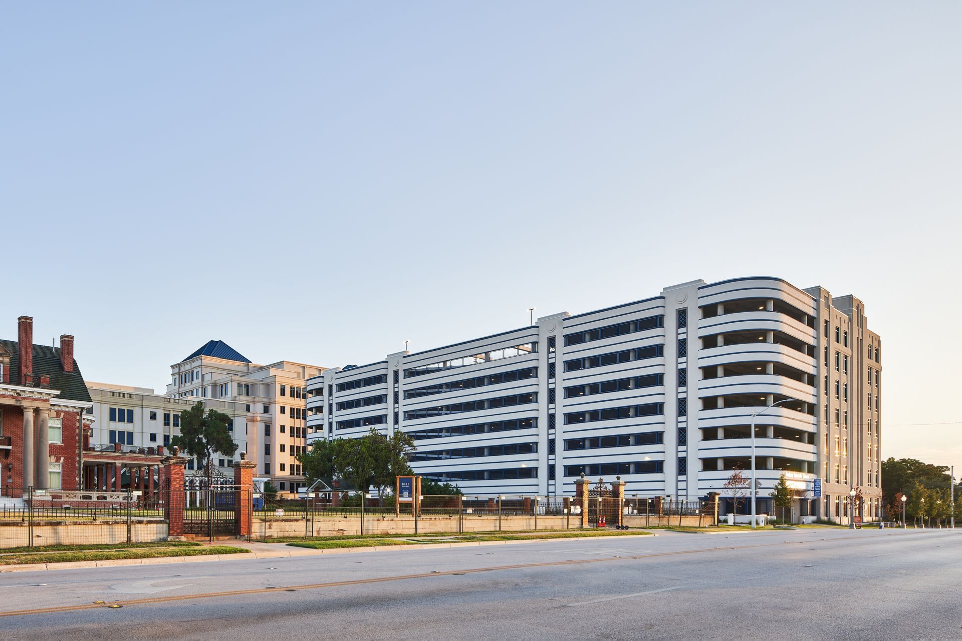 White multi-story parking garage with a curved facade under a clear blue sky.