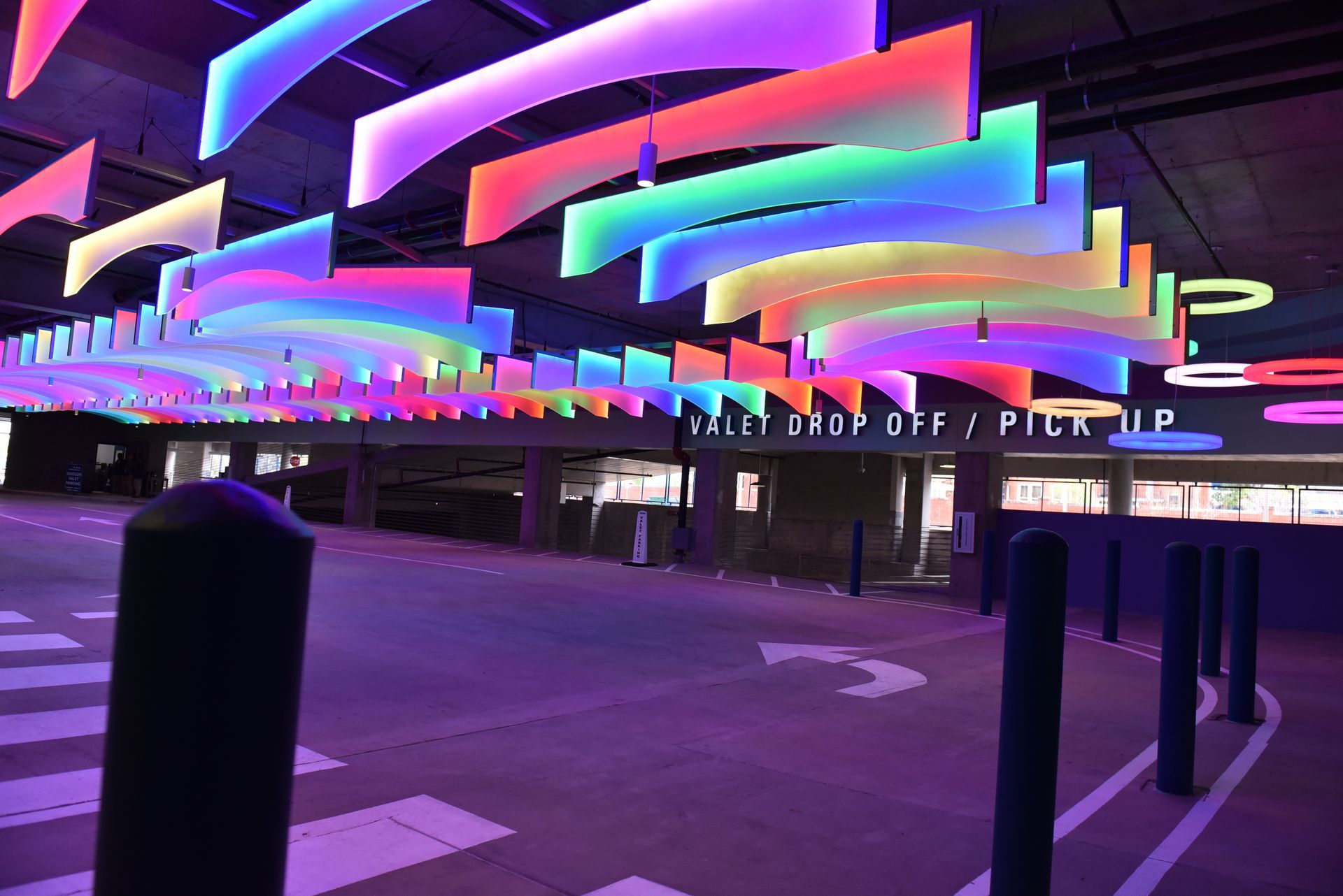 Colorful light installation above a valet drop-off area.