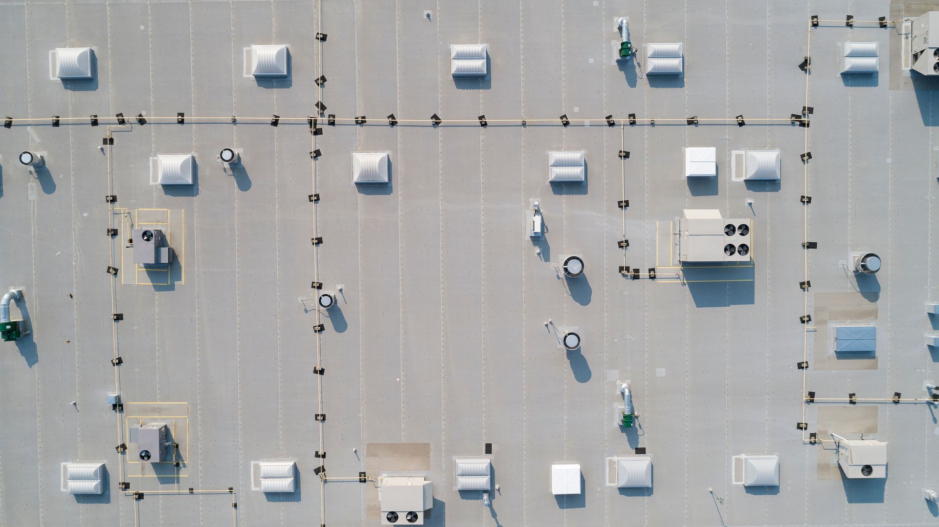 Aerial view of a flat rooftop with HVAC units, vents, and scattered maintenance workers.