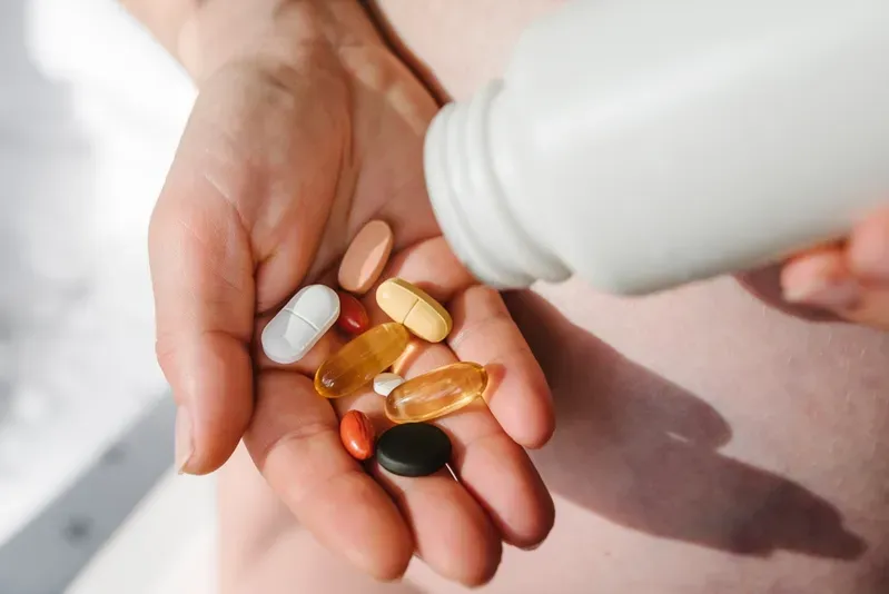 A person is pouring pills from a bottle into their hand.