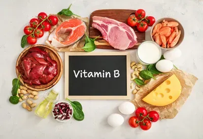A blackboard with the word vitamin b written on it surrounded by different types of food.