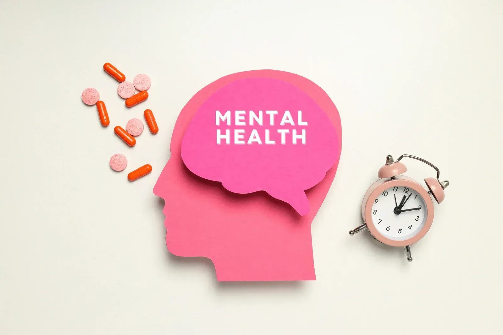 A pink head with a speech bubble that says mental health next to a clock and pills.