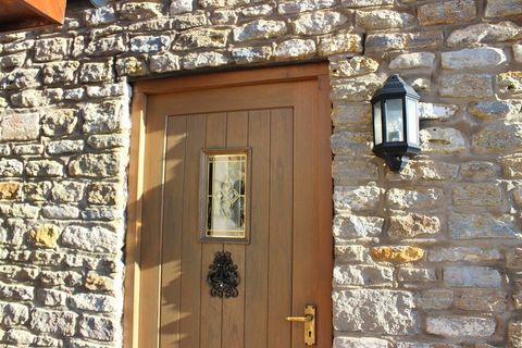 Photo showing a traditional wooden door on an English country cottage with an irregular stone wall.