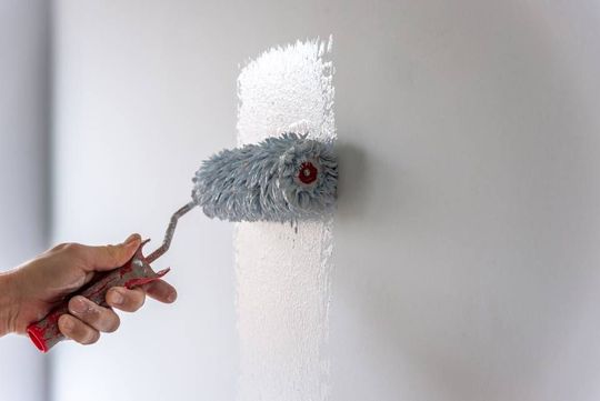 worker painting the wall with the roller