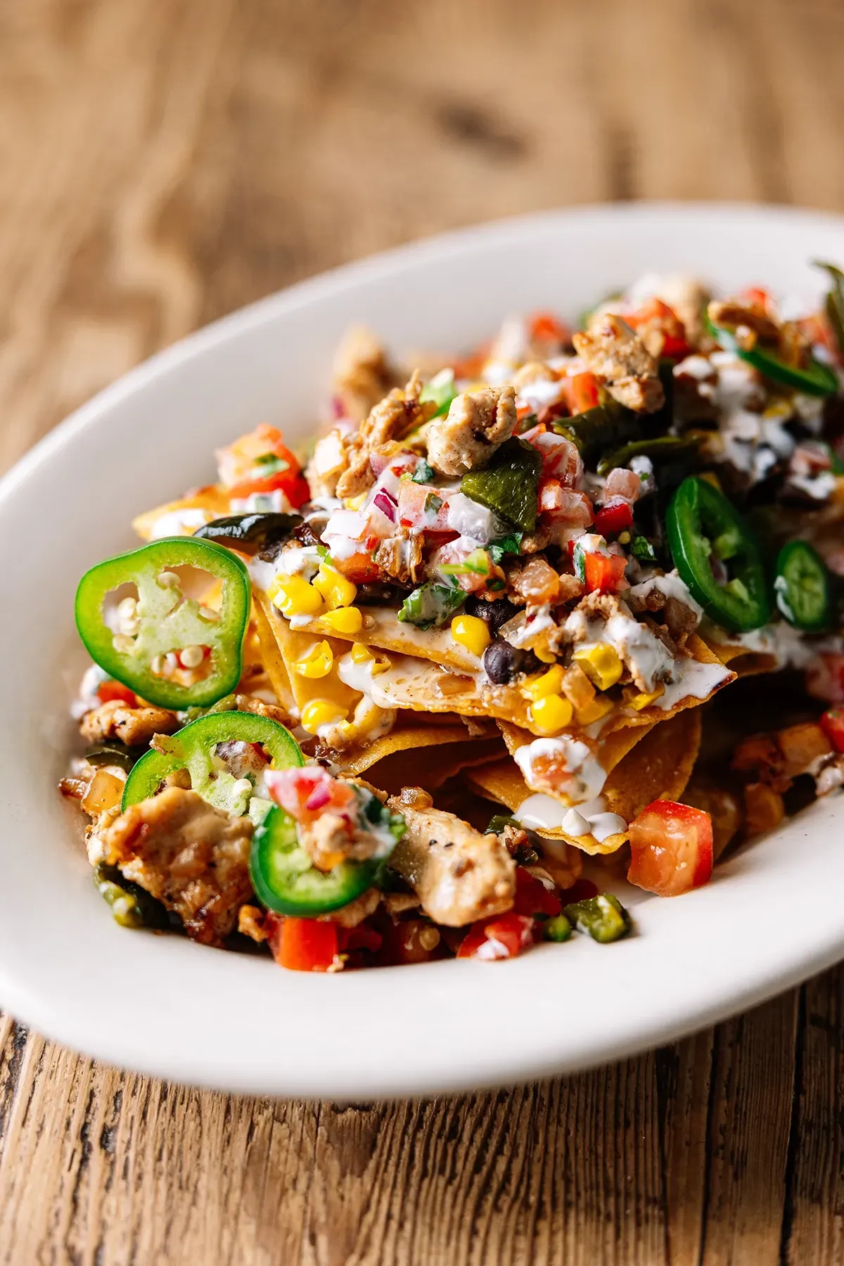 A white plate topped with nachos and vegetables on a wooden table.