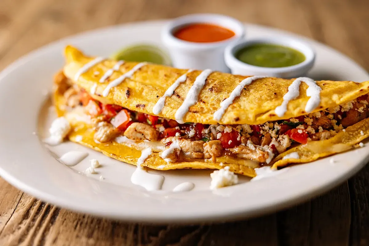 A close up of a plate of food with sauces on a wooden table.