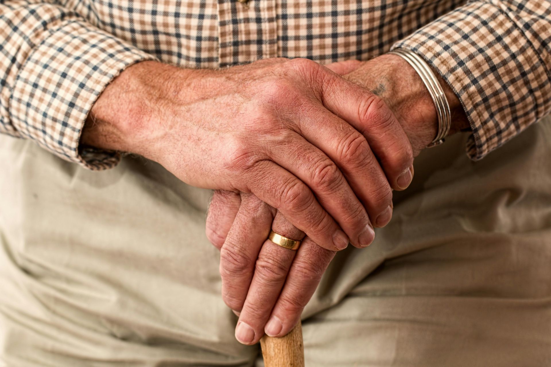 A man with a ring on his finger is holding a cane.