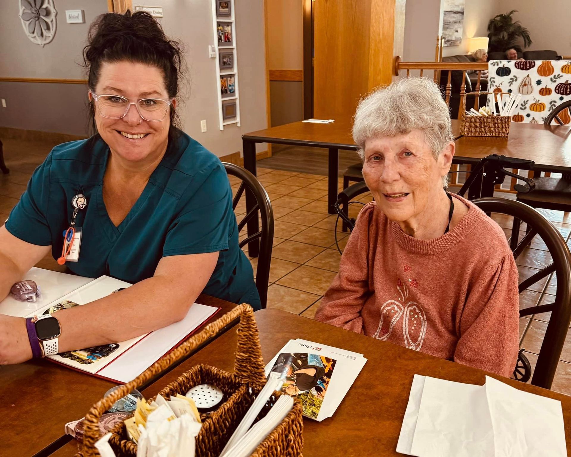 A nurse and an elderly woman are sitting at a table.