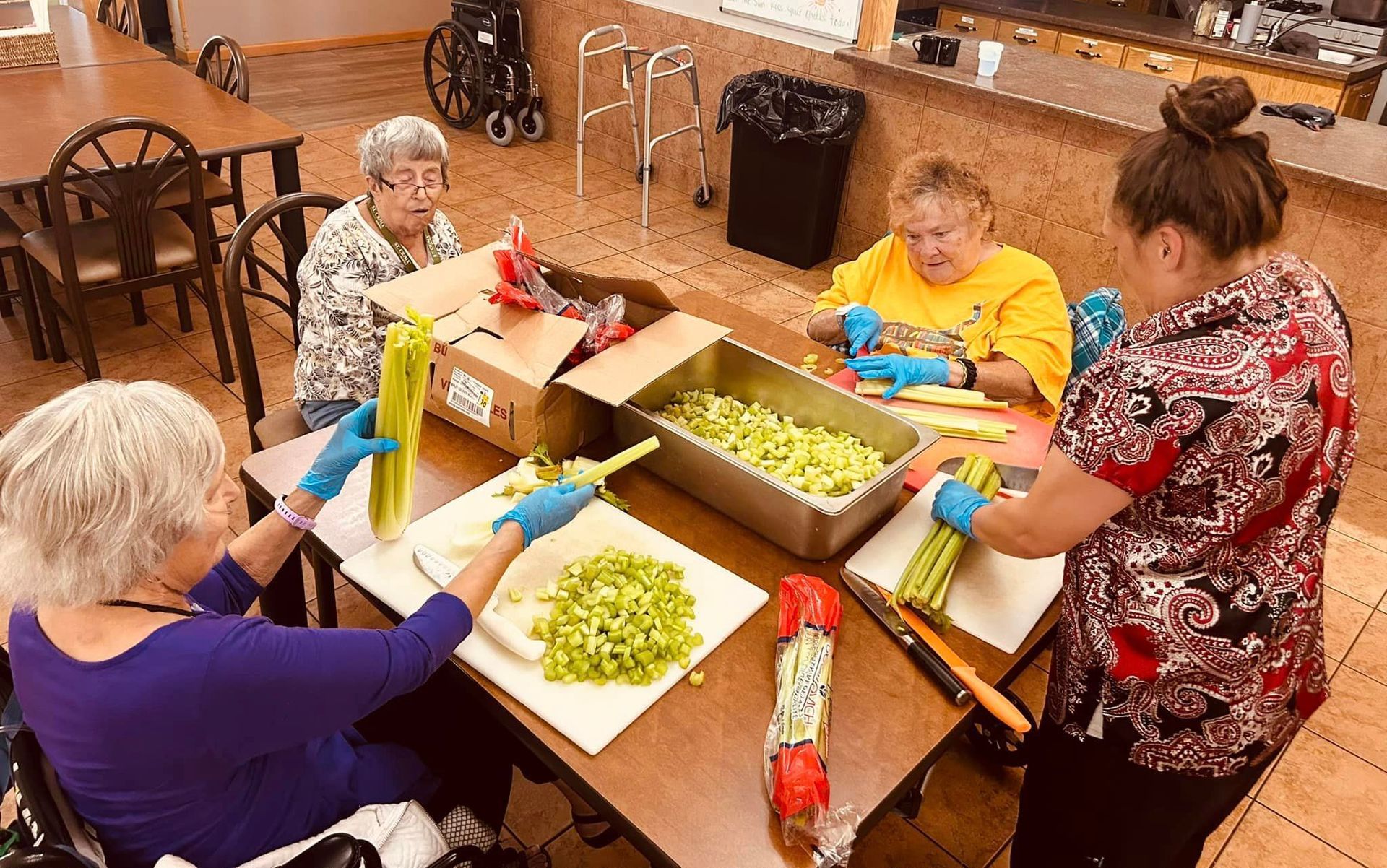 A group of people are sitting around a table cutting vegetables.