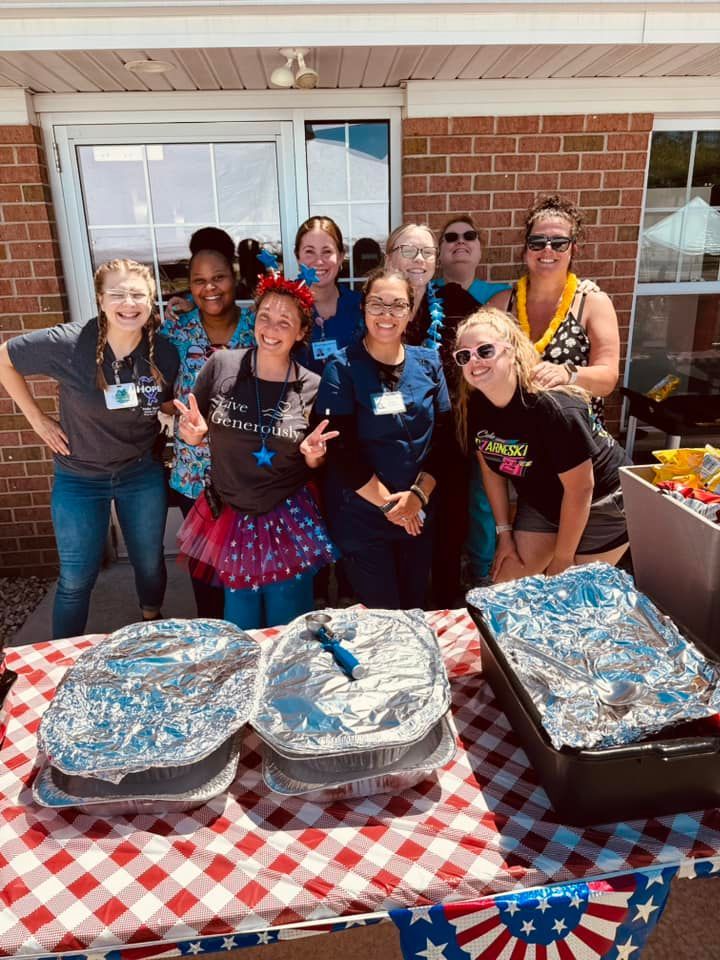 The Tender Hearts team is posing for a picture in front of a table with food on it.