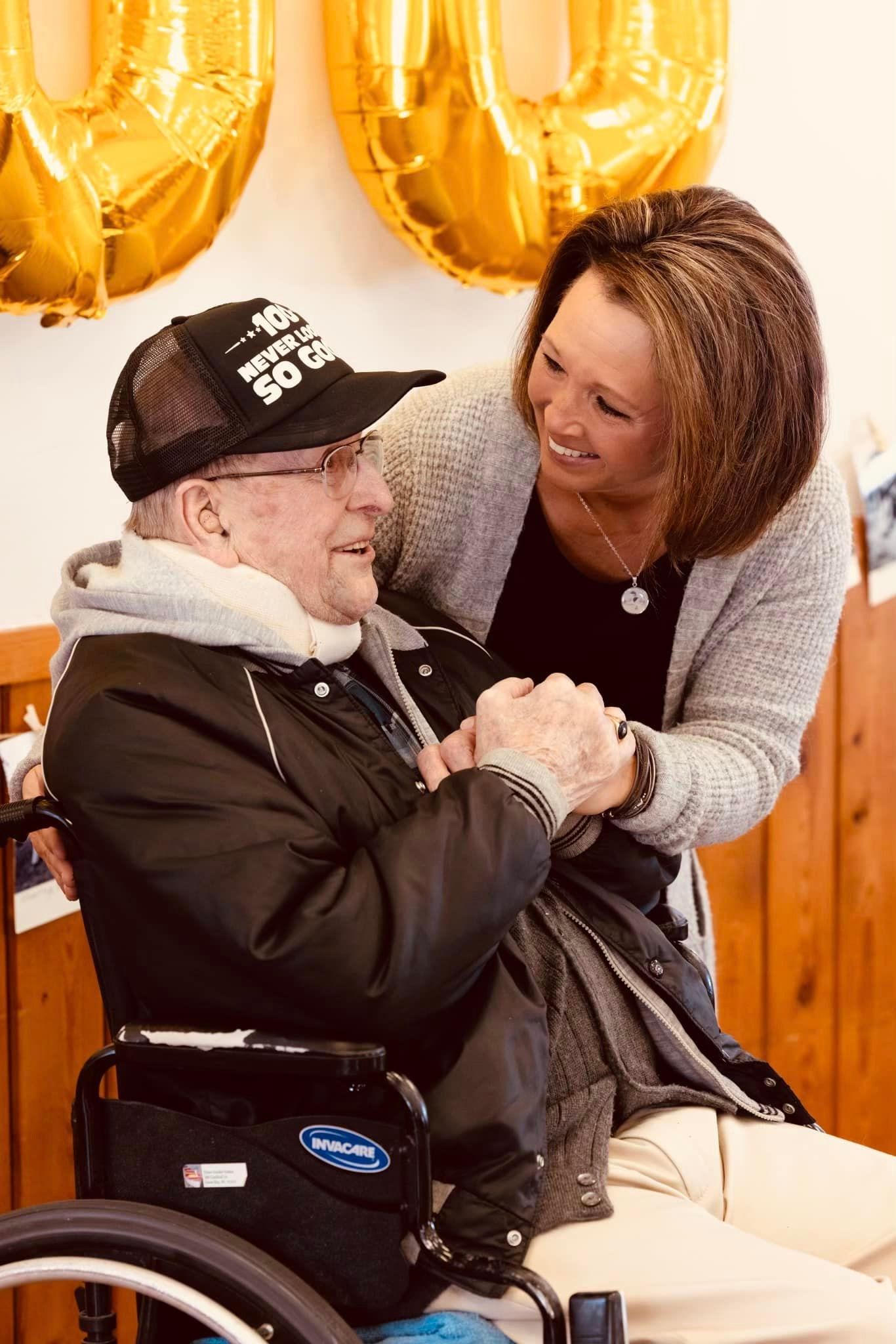 A woman is hugging a man in a wheelchair.