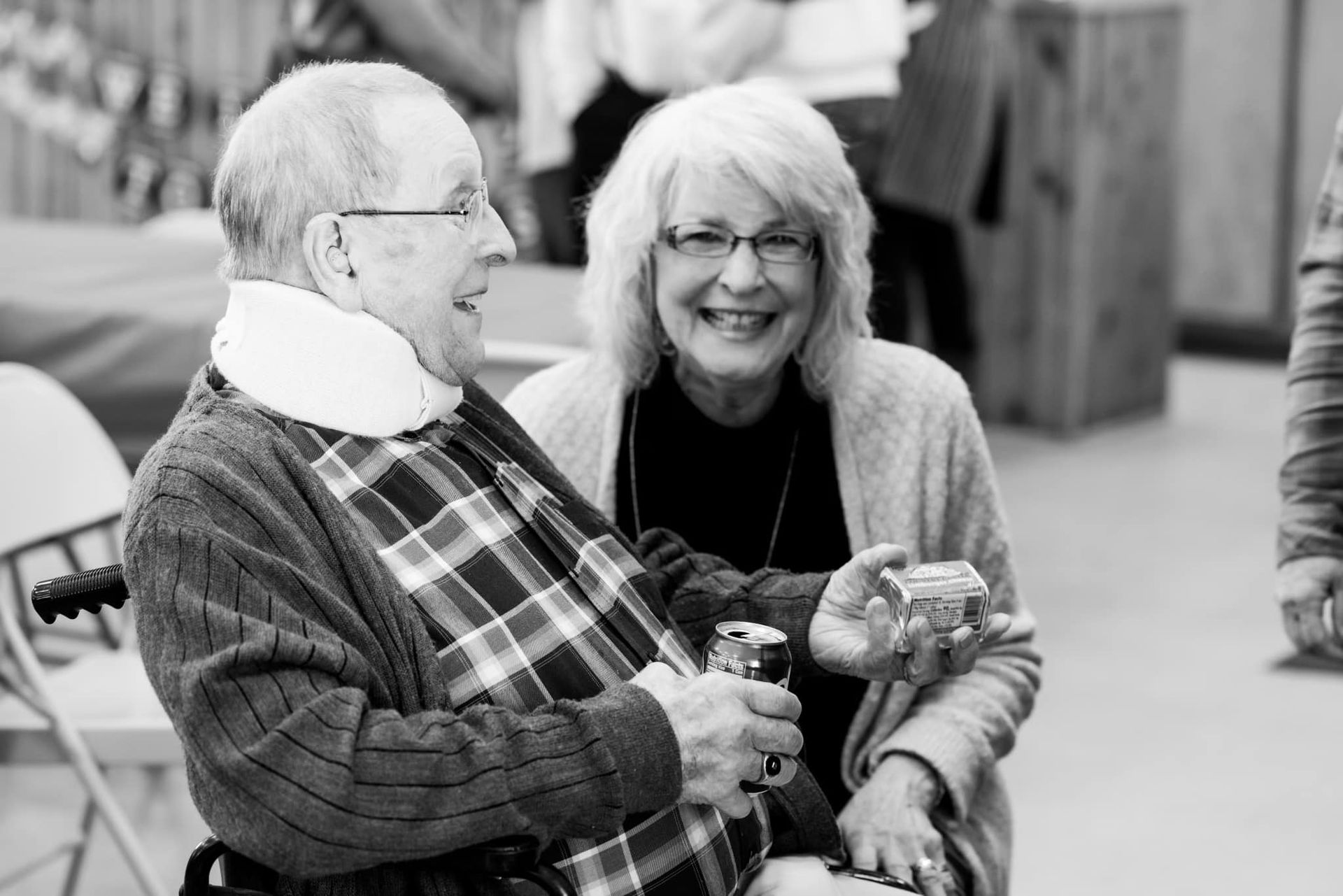 A man in a wheelchair is sitting next to a woman in a black and white photo.