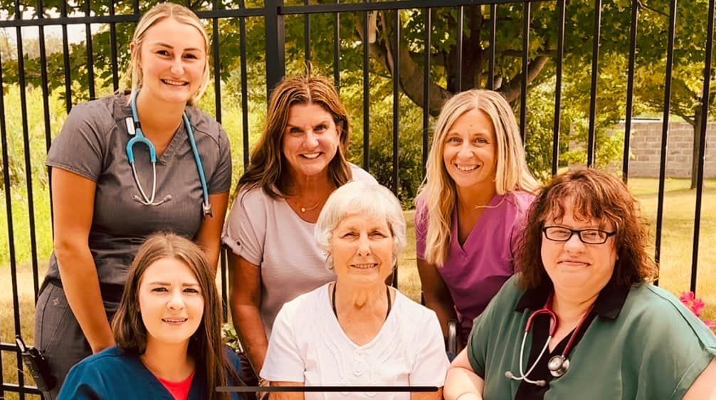 The Tender Hearts team is posing for a picture in front of a fence.