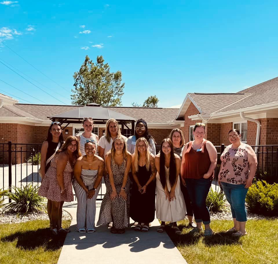 The Tender Hearts team is posing for a picture in front of a brick building.