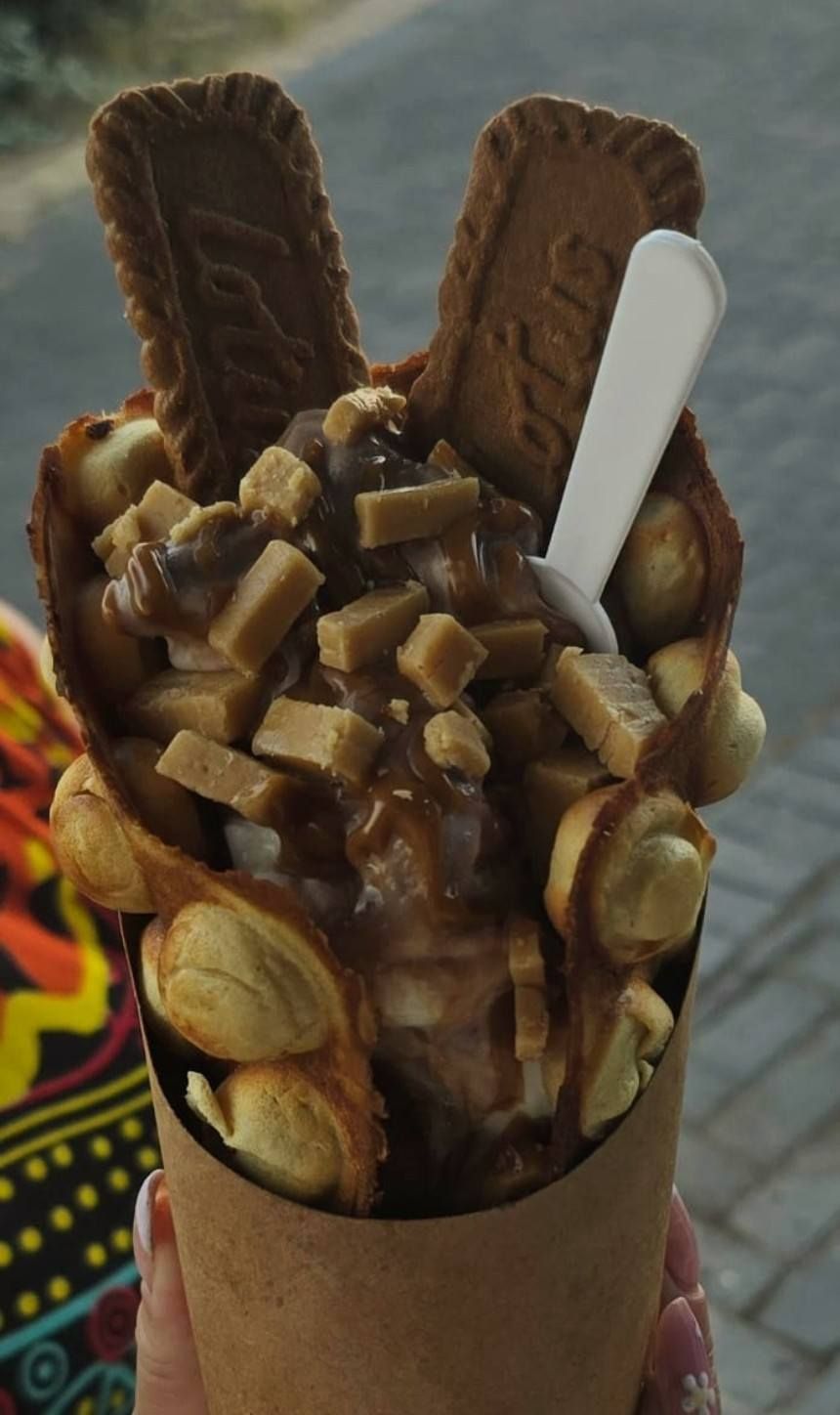 Bubble waffle cone filled with whipped cream, popcorn, chocolate sticks, and marshmallow.