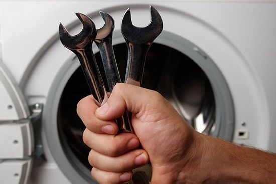mano stringe attrezzi per riparare lavatrice