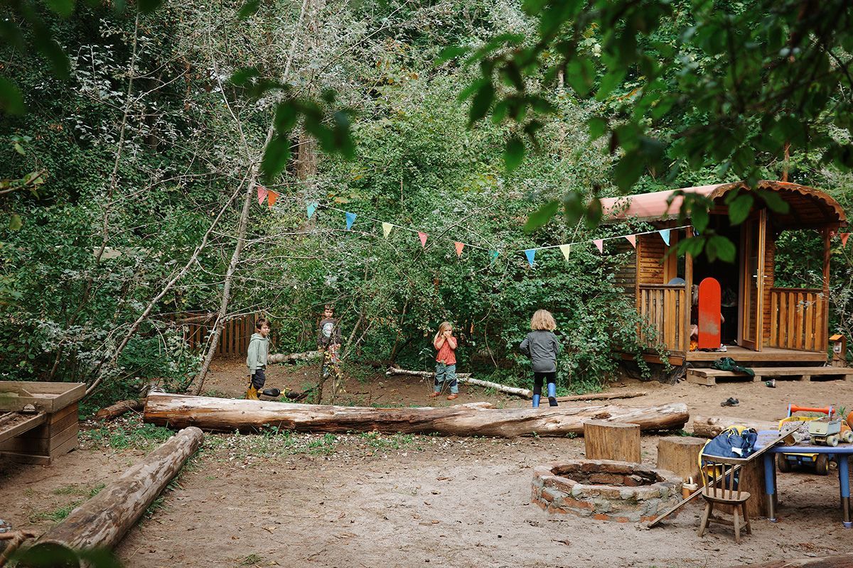 Kinder spielen im Waldgarten, Feuerstelle, Zirkuswagen