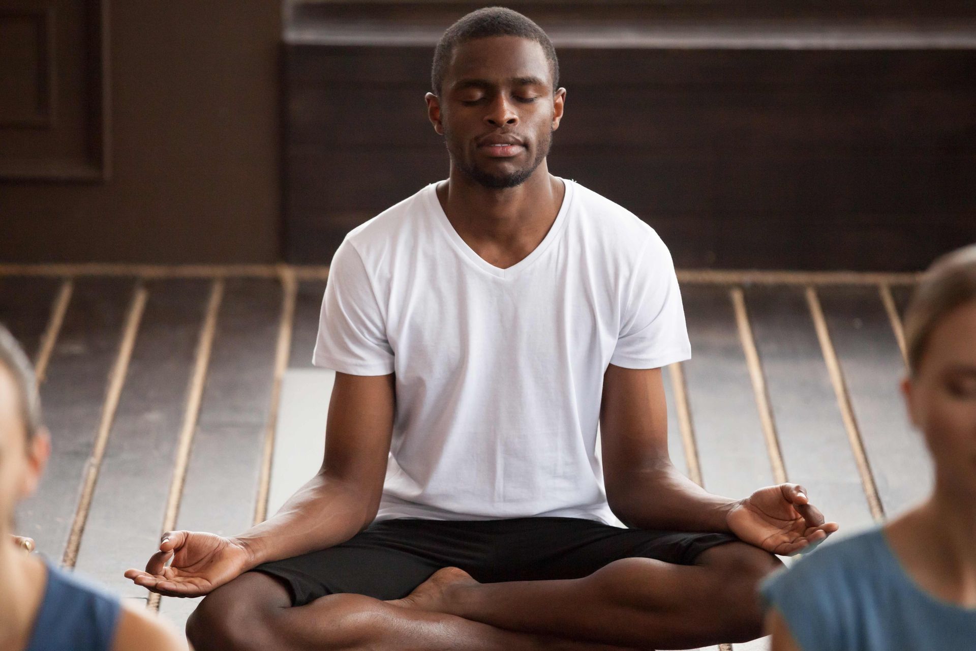 a man is sitting in a lotus position with his eyes closed in a yoga class