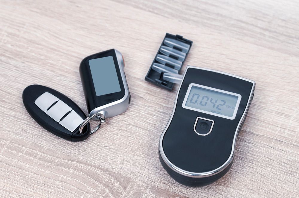 A Car Alarm and A Digital Alcohol Tester on A Wooden Table — A & K Auto Electrical & Air Conditioning in Scone, NSW