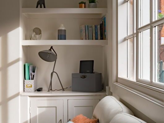 A corner of a room with shelves and a lamp