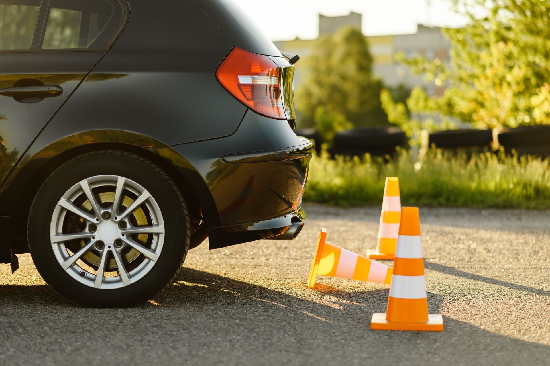 Black car next to orange and white traffic cones on asphalt.