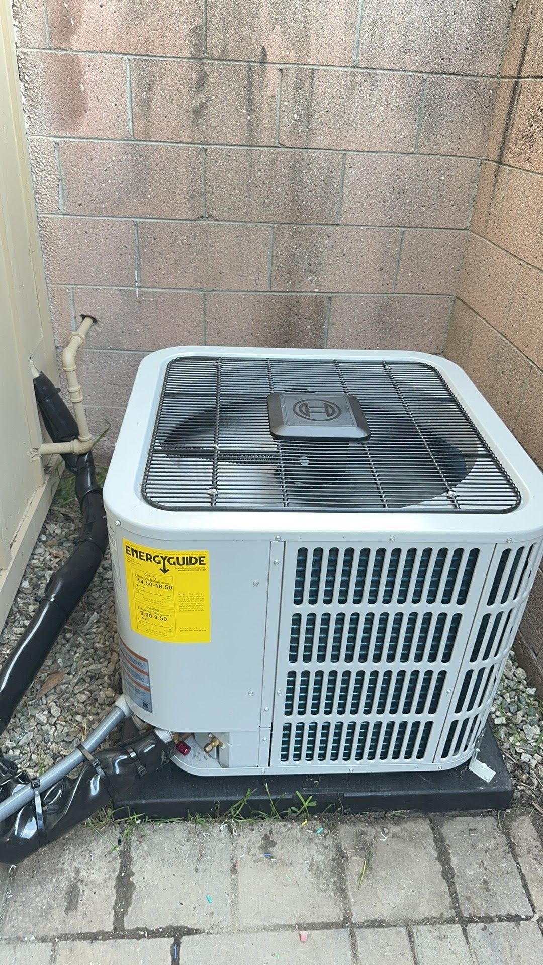 An outdoor air conditioning unit next to a brick wall.