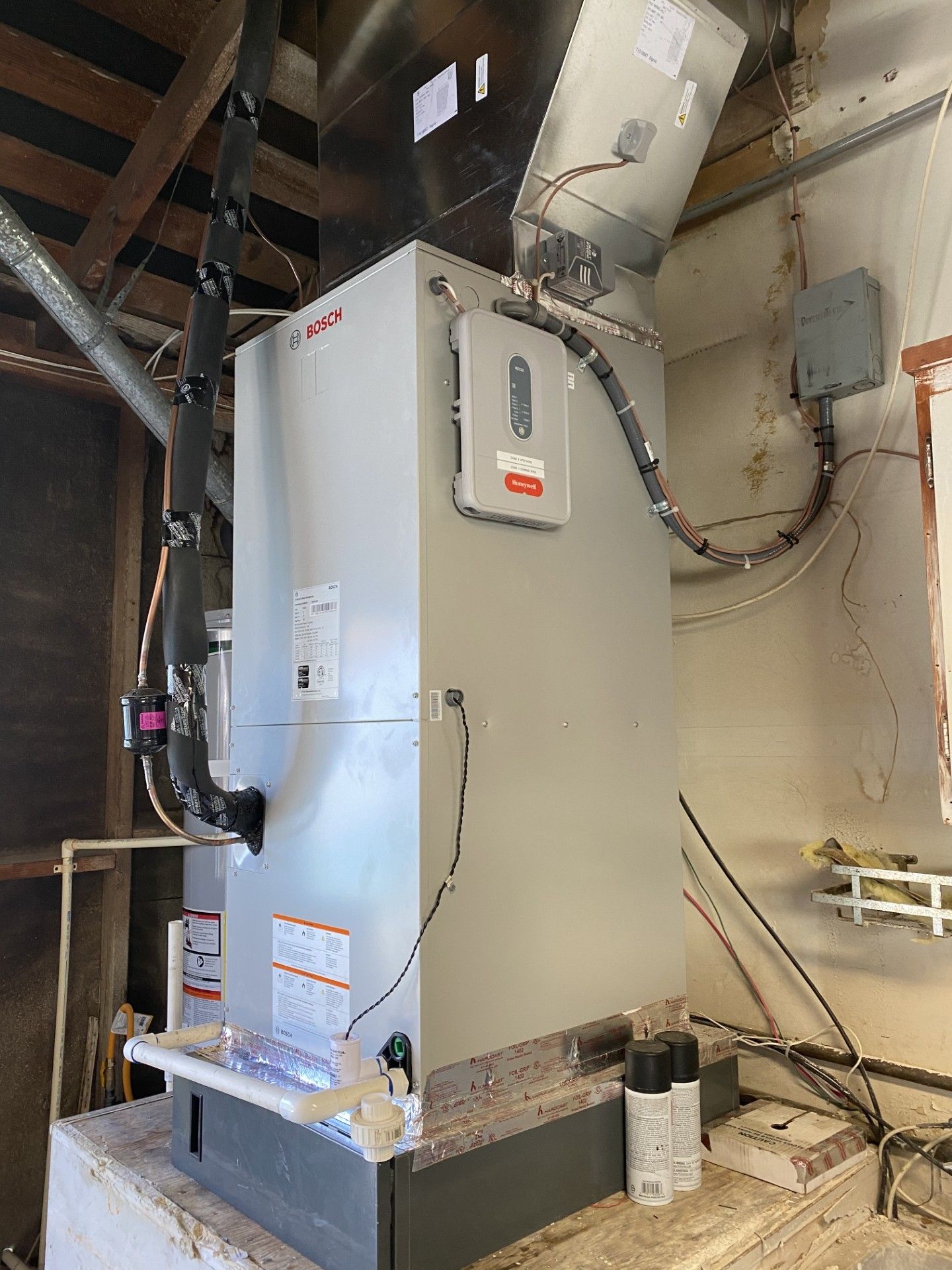 Large grey Lennox furnace in a utility room. Ductwork, electrical components, and insulation visible.